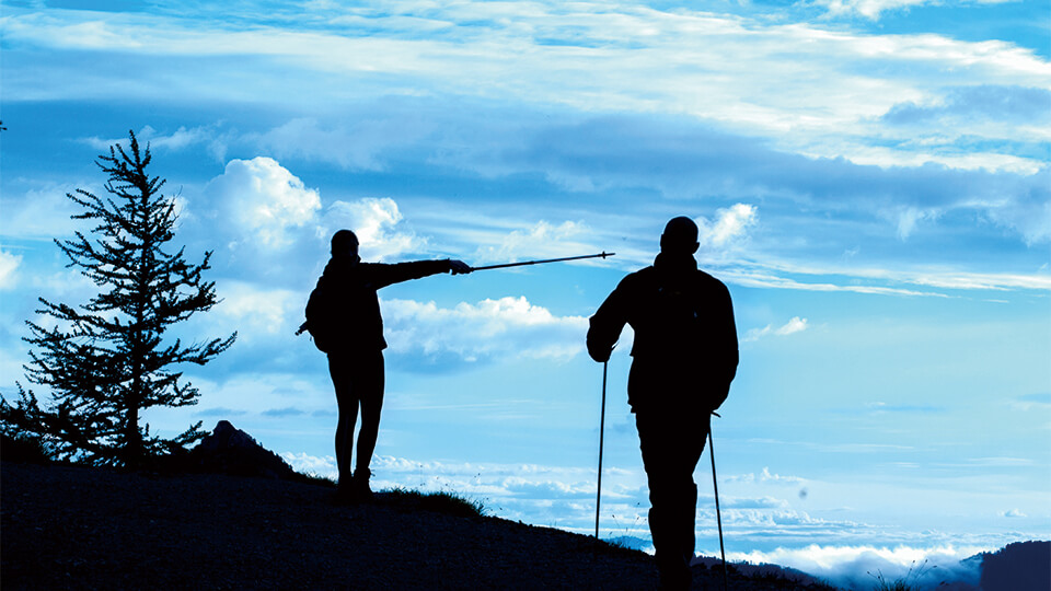 杖をつきながら富士登山をしている二人組のシルエット