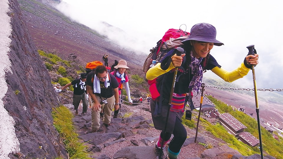 登山道を杖をつきながら登る女性