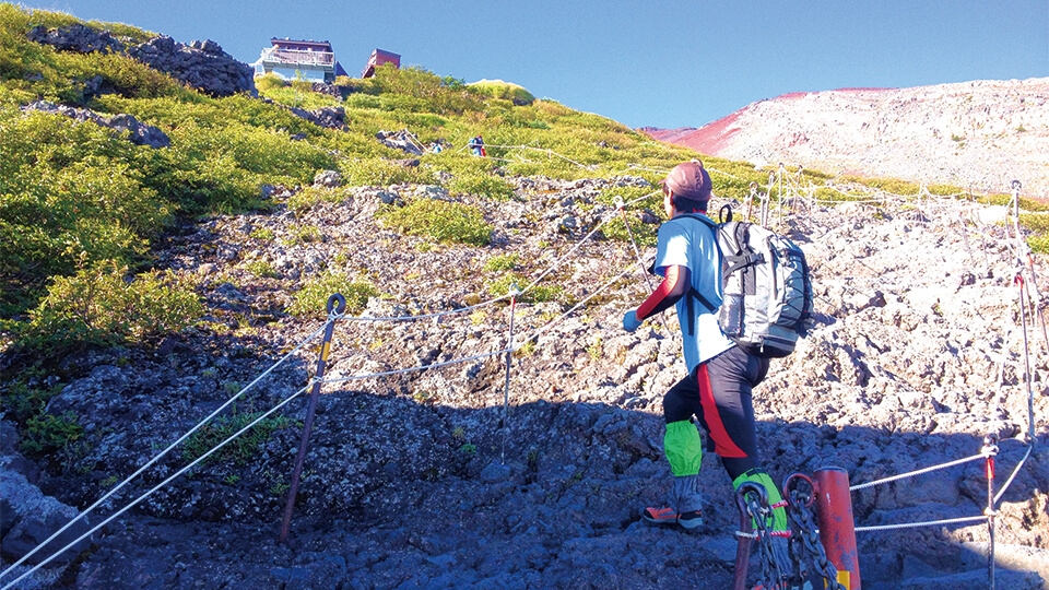 晴れた日に富士山登山道を登る女性