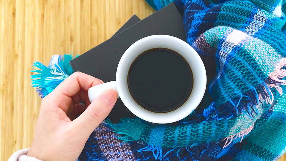 白いカップに入ったホットコーヒーとブランケット