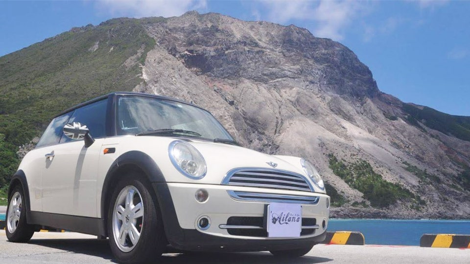 神津島の山の前に止まっているミニクーパー