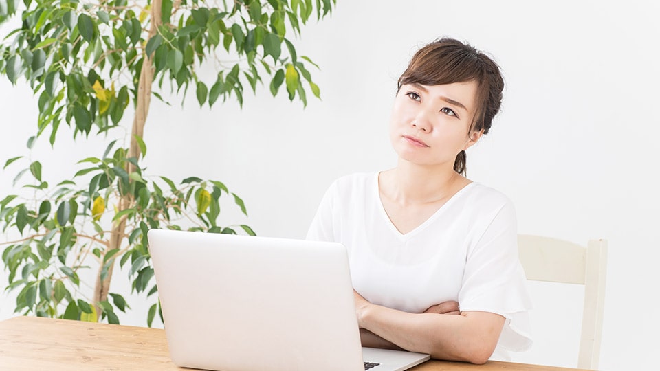 パソコンで宿探しをしながら考えている女性のイメージ